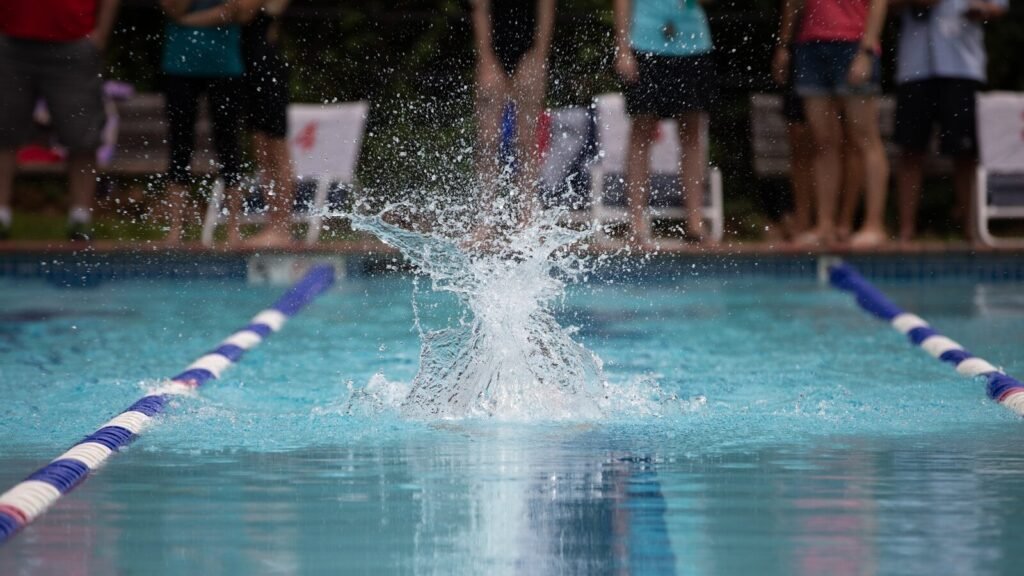 a person jumping into a swimming pool with their arms in the air