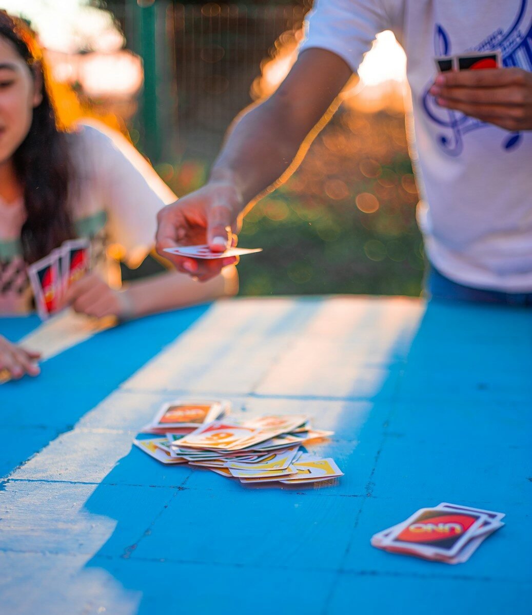 Family playing the card game Uno outside on a summer day.